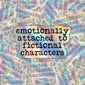May include: A holographic sticker with the text "emotionally attached to fictional characters" in black typewriter font.