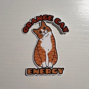 Peut inclure: Autocollant de chat orange avec le texte "Orange Cat Energy" dans une police de caract&egrave;res r&eacute;tro.