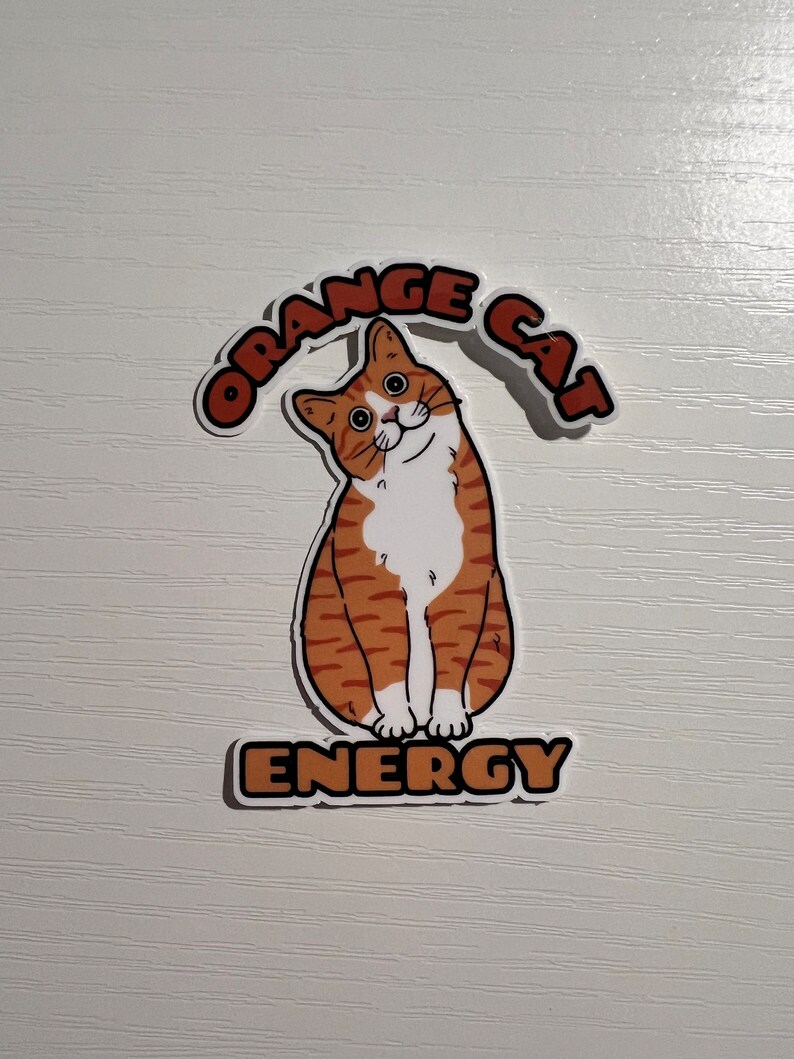 Peut inclure: Autocollant de chat orange avec le texte "Orange Cat Energy" dans une police de caract&egrave;res r&eacute;tro.
