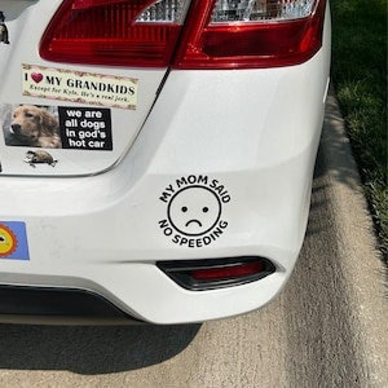 Op de afbeelding: Een zwart-witte auto sticker met de tekst "My Mom Said No Speeding" en een emoji met een verdrietig gezicht.