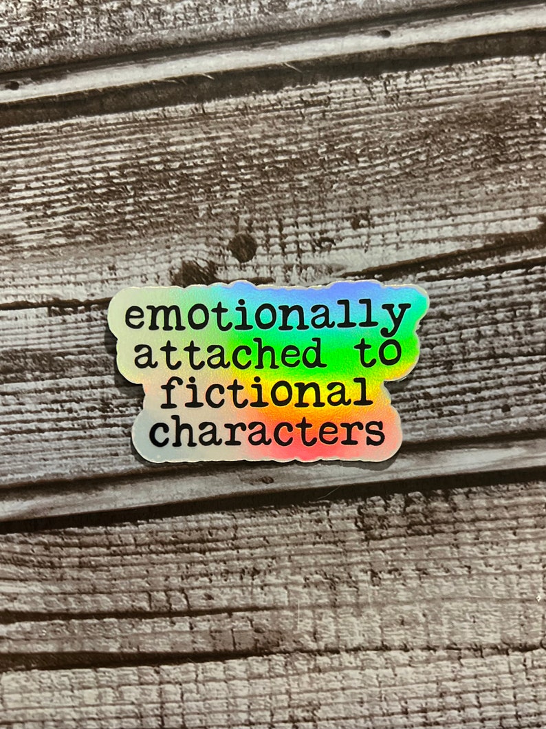 May include: A rainbow holographic sticker with the text "emotionally attached to fictional characters".