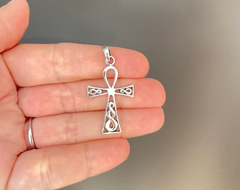 May include: A silver pendant in the shape of an Ankh, an ancient Egyptian symbol of life. The pendant has a detailed, intricate design.