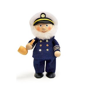 May include: A wooden figurine of a sailor wearing a blue uniform with gold buttons, a white hat with a gold band, and a white beard. The sailor is holding a wooden pipe in his right hand.