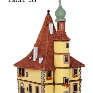 May include: A yellow ceramic building with a brown roof and a green spire. The building has windows and a door. The text "RodT 18" is visible on the image.