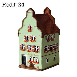May include: A green and brown ceramic model of a building with a red roof and white windows. The building has a sign that reads "Gasthof - Greifen".