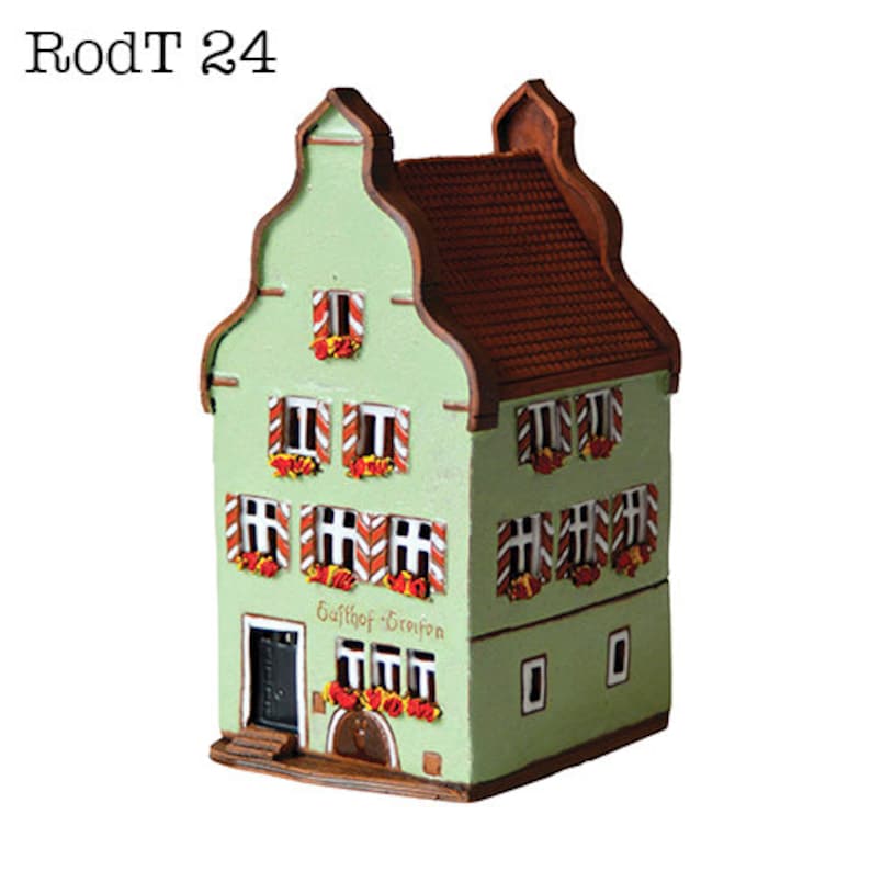 May include: A green and brown ceramic model of a building with a red roof and white windows. The building has a sign that reads "Gasthof - Greifen".