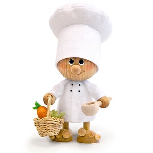 May include: A wooden figurine of a chef wearing a white chef's hat and a white uniform. The chef is holding a wooden ladle and a basket of carrots.