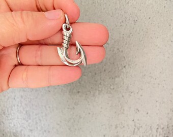 以下が含まれることがあります： 詳細なデザインが施された銀製のフックチャーム。フックは幸運と繁栄の象徴として人気があります。