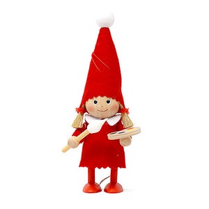 May include: A red felt Christmas elf doll with a white pom-pom hat, holding a paintbrush and a wooden paint palette.
