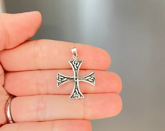 May include: A silver pendant in the shape of a cross with intricate knotwork details.