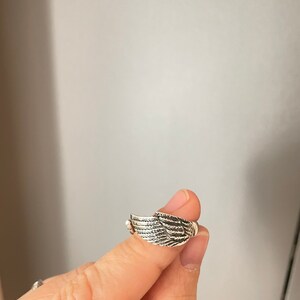 May include: A silver ring with a detailed wing design.