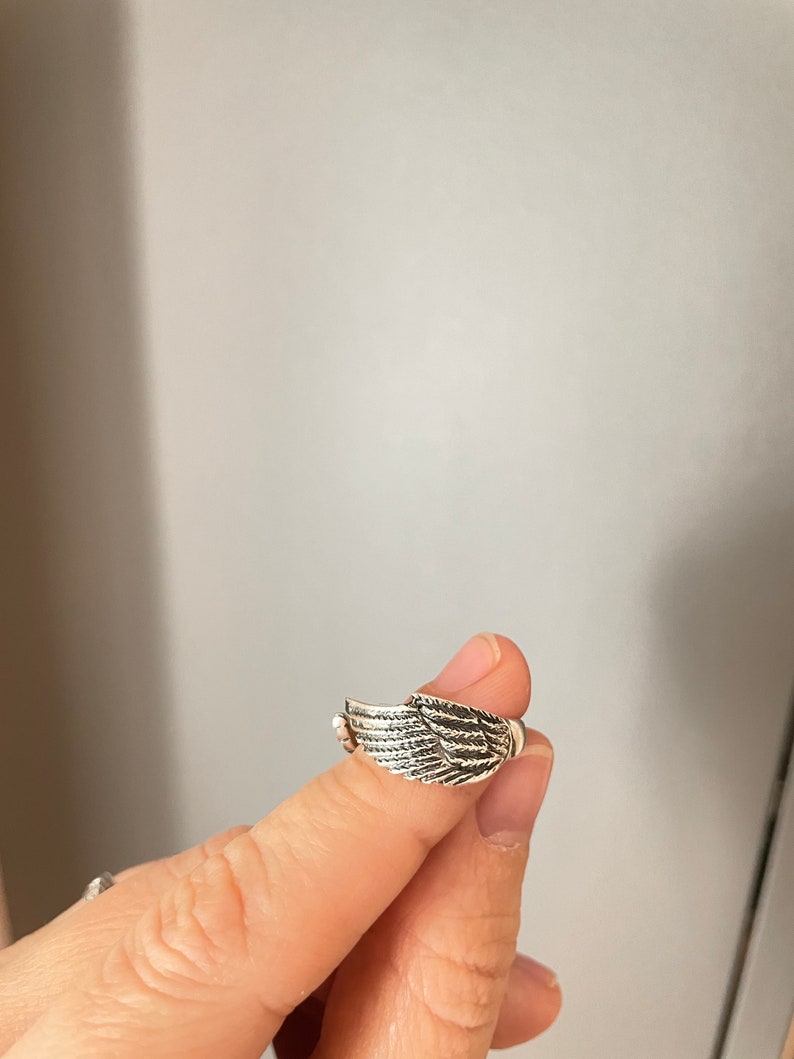 May include: A silver ring with a detailed wing design.