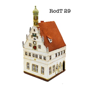 May include: A white and red miniature model of a building with a clock tower and a red roof. The building has a sign that reads "RodT 29".