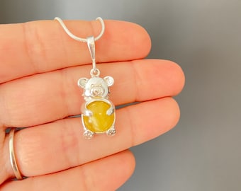May include: A silver necklace with a yellow gemstone teddy bear pendant.