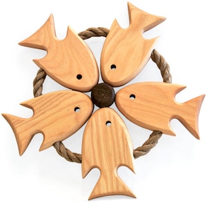 May include: A set of five wooden fish-shaped trivets arranged in a circle, connected by a brown rope. The trivets are made of light wood with a natural finish.