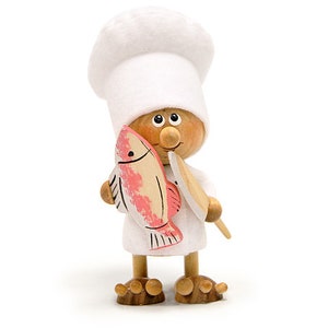 May include: A wooden figurine of a chef wearing a white hat and holding a pink fish and a wooden spatula.