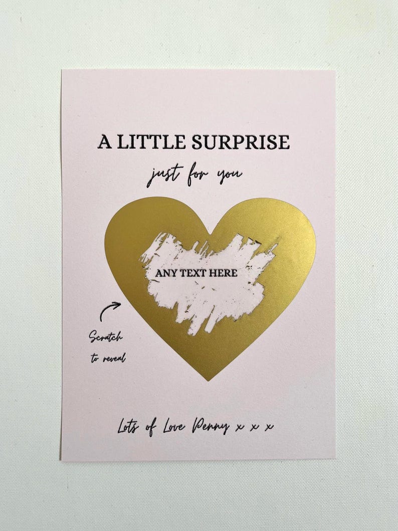 Puede incluir: Tarjeta rosa con el texto "A LITTLE SURPRISE just for you". Un coraz&oacute;n dorado para rascar en el centro, con "ANY TEXT HERE" encima. La parte inferior dice "Lots of Love Penny x x x." Instrucciones "Scratch to reveal."