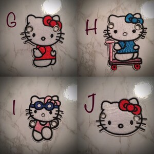 May include: Four embroidered iron-on patches featuring Hello Kitty in different outfits. The patches are white with black outlines and feature different colored accents. The first patch shows Hello Kitty wearing a red shirt, the second shows Hello Kitty riding a scooter, the third shows Hello Kitty wearing a swimsuit and goggles, and the fourth shows Hello Kitty with a red bow.