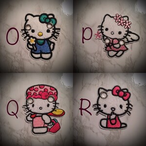 May include: Four embroidered Hello Kitty patches with different outfits. The patches are white with black outlines and feature Hello Kitty with different accessories. The patches are labeled with the letters O, P, Q, and R.