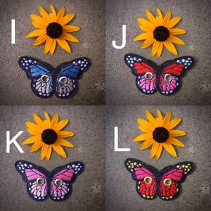 Peut inclure: Quatre patchs de papillon brod&eacute;s avec des points noirs et deux &oelig;illets. Les papillons sont bleus, roses, rouges et rouges avec des accents jaunes. Chaque papillon est affich&eacute; sur un fond gris avec un tournesol jaune.