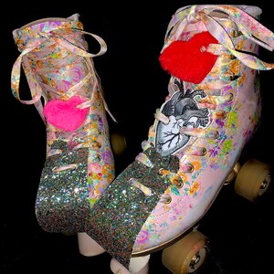 May include: A pair of pink roller skates with floral print and glitter accents. The skates have red and pink heart-shaped charms and a black and white anatomical heart patch.