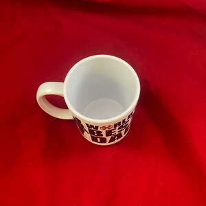 A top-down view of a mug inspired by the RE universe, specifically Village, with the words World's Best Dad in stylized caps, along with a silhouette of the main character.