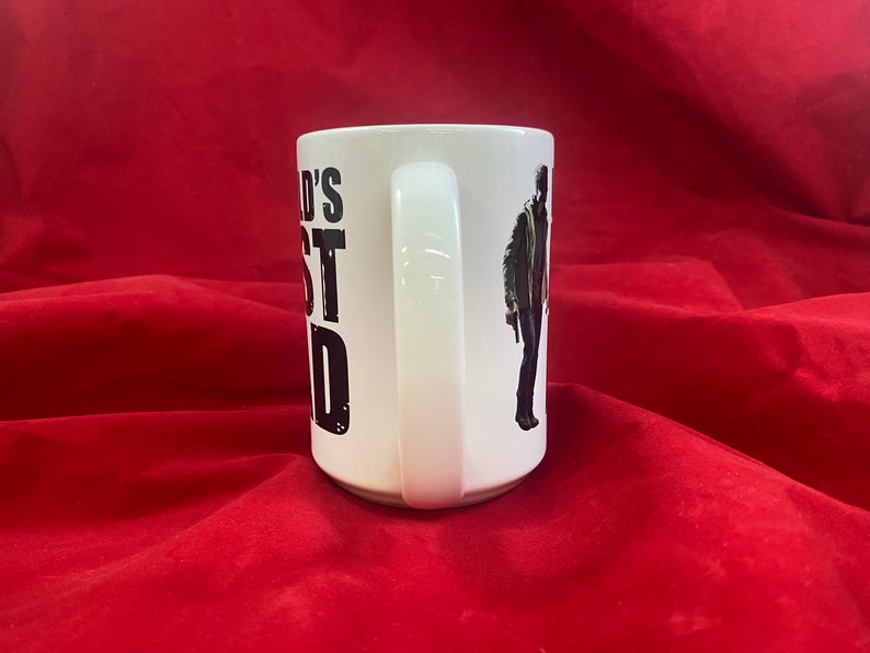 Handle view of a coffee mug inspired by the RE universe, specifically Village, with the words World's Best Dad in stylized caps, along with a silhouette of the main character.