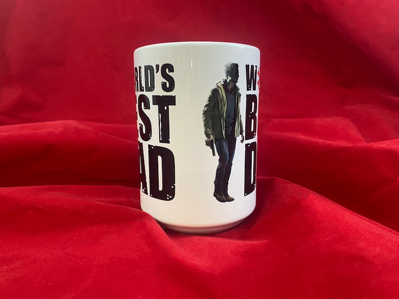 A front view of a mug inspired by the RE universe, specifically Village, with the words World's Best Dad in stylized caps, along with a silhouette of the main character.