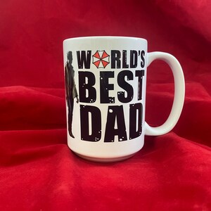 A two-sided mug inspired by the RE universe, specifically Village, with the words World's Best Dad in stylized caps, along with a silhouette of the main character.