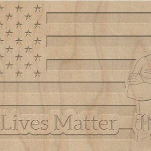 Puede incluir: Un letrero de madera con un diseño de bandera estadounidense y el texto "Blue Lives Matter". Un policía de dibujos animados está de pie a la derecha de la bandera.