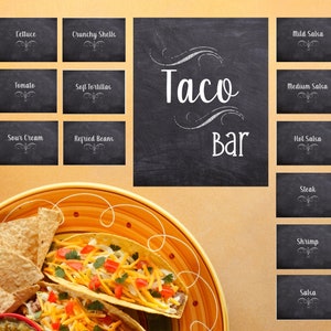 May include: A vibrant image showcasing a taco bar setup. The scene includes a plate of tacos with toppings, tortilla chips, and guacamole. Black chalkboards list ingredients like lettuce, tomatoes, and various salsas. The words "Taco Bar" are prominently displayed.
