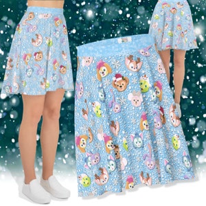 May include: A light blue skater skirt featuring a repeating pattern of cartoon character faces and snowflakes. The skirt has a light blue waistband and a flared silhouette. The characters are in various colors, with some wearing winter hats.