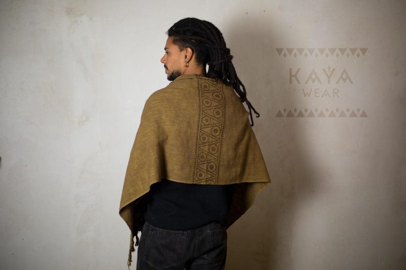 May include: A person wearing a brown shawl with a geometric pattern. The shawl is made of a soft, woven fabric. The text "KAYA WEAR" is visible in the top right corner of the image.