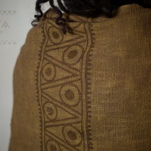 May include: A brown linen scarf with a dark brown geometric pattern. The pattern features circles and triangles.