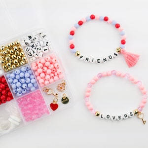 May include: A kit for making friendship bracelets with colorful beads, letter beads, and charms. The kit includes beads in pink, red, white, blue, and gold. The letter beads spell out "FRIENDS" and "LOVERS".