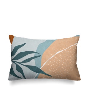 May include: A rectangular pillow with a light blue, orange, and brown abstract design. The design features a stylized leaf with a textured background.