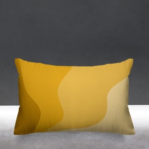 Puede incluir: Una almohada rectangular con un patr&oacute;n abstracto amarillo y beige. La almohada tiene una tela suave y texturizada.