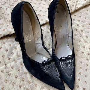 May include: A pair of black pointed-toe court shoes featuring a textured black lace overlay on the vamp. The interior lining is light-coloured with the text "Personally" printed in gold script on the heel bed of each shoe, set on a high stiletto heel.