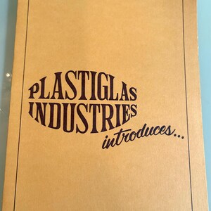 May include: A tan brochure with a black border and the text "PLASTIGLAS INDUSTRIES introduces..." in a stylized font. The brochure has a simple, vintage design, with the text arranged in a curved layout.