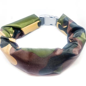 May include: A camouflage-patterned adjustable belt with a silver buckle. The belt is made of a soft, water-resistant fabric.