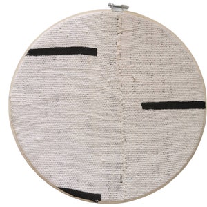 May include: A white circular embroidery hoop with black lines painted across the fabric.