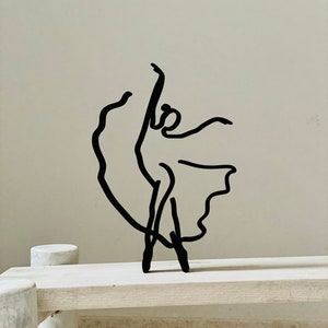 May include: Black metal sculpture of a ballerina in a flowing skirt pose.