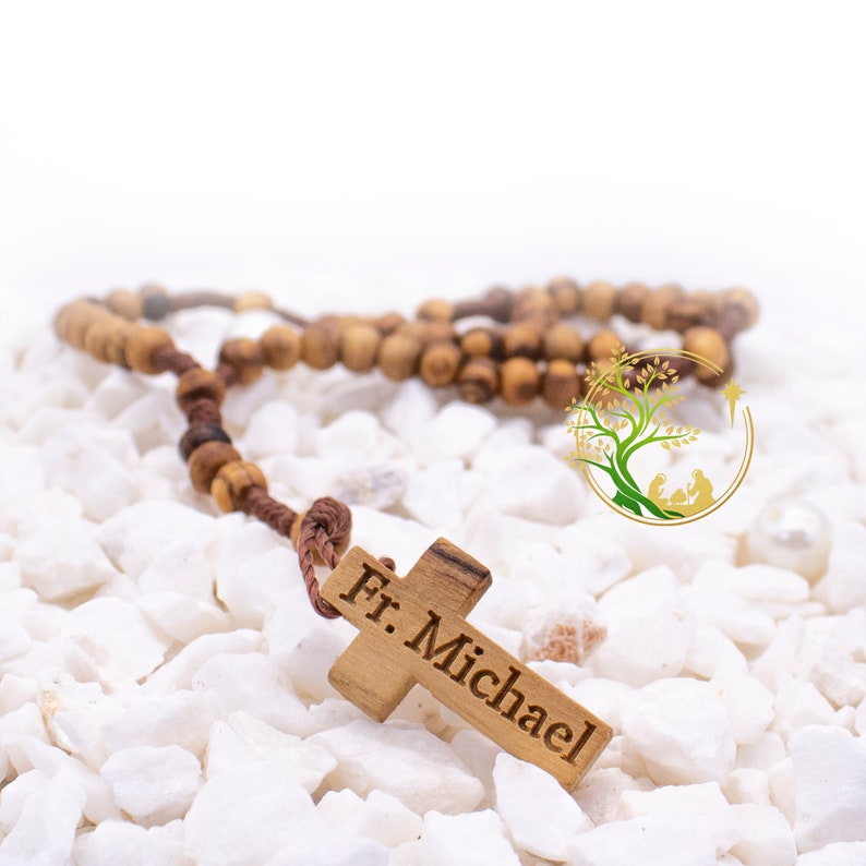 May include: A wooden rosary with a brown cord and a wooden cross with the inscription "Fr. Michael".