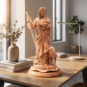 Op de afbeelding: Gedetailleerd houten beeld van een figuur met lang haar en een baard, die een staf en een lam vasthoudt. Het beeld is lichtbruin en staat op een ronde basis. De figuur draagt een gedrapeerde jurk. Het beeld staat op een houten bureau.
