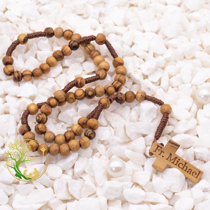 May include: A brown wooden rosary with a brown cord and a wooden cross with the inscription "Fr. Michael".