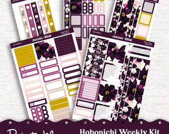 Op de afbeelding: Printbare Hobonichi Weekly Kit-stickers in een bloemmotief met paarse, roze en gouden accenten. De set bevat stickers voor de dagen van de week, vakjes en andere belangrijke plannerbenodigdheden. De tekst "Jacmo Blue" staat op de stickers.