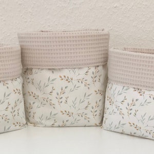 May include: Three beige fabric storage baskets with a white and brown floral pattern. The baskets have a beige waffle-textured top.