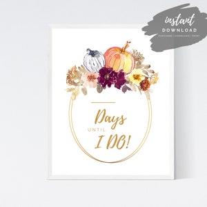 May include: A printable wedding countdown sign with a gold circle frame and watercolor floral design featuring pumpkins, leaves, and flowers in shades of orange, yellow, burgundy, and white. The text reads "Days Until I Do!"