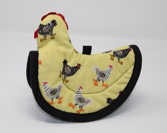 Puede incluir: Un posavasos amarillo con forma de pollo, con un borde negro y una cresta roja. El posavasos está cubierto con un patrón de pollos negros y blancos.