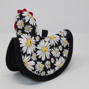 May include: Black and white pot holder shaped like a chicken with a red comb and white daisy print.